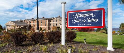 A Hampton Inn & Suites sign with a view of the hotel building in the background.