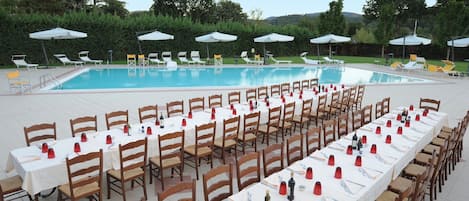 Una piscina al aire libre, sombrillas, sillones reclinables de piscina