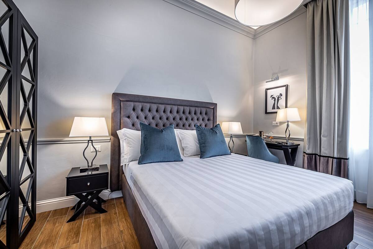 A neatly arranged hotel room with a large bed, two bedside tables, and a modern lamp.