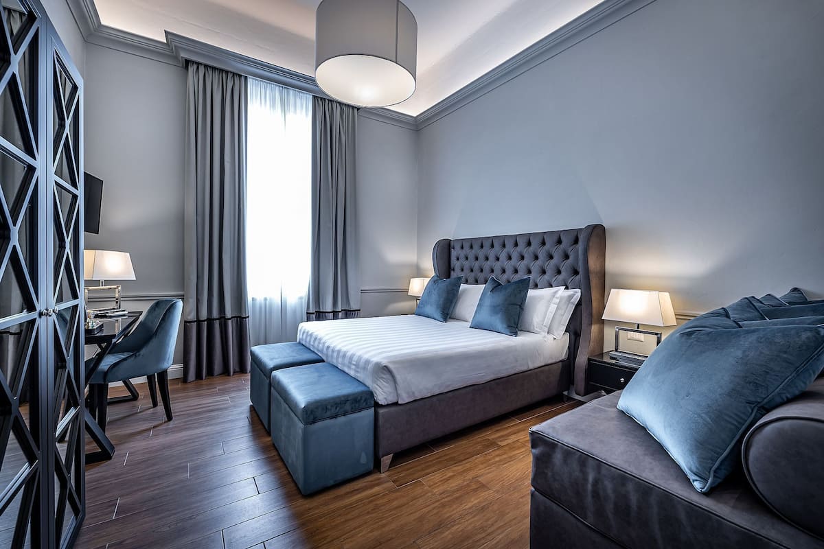 A modern hotel room with a large bed, a desk, and a seating area.
