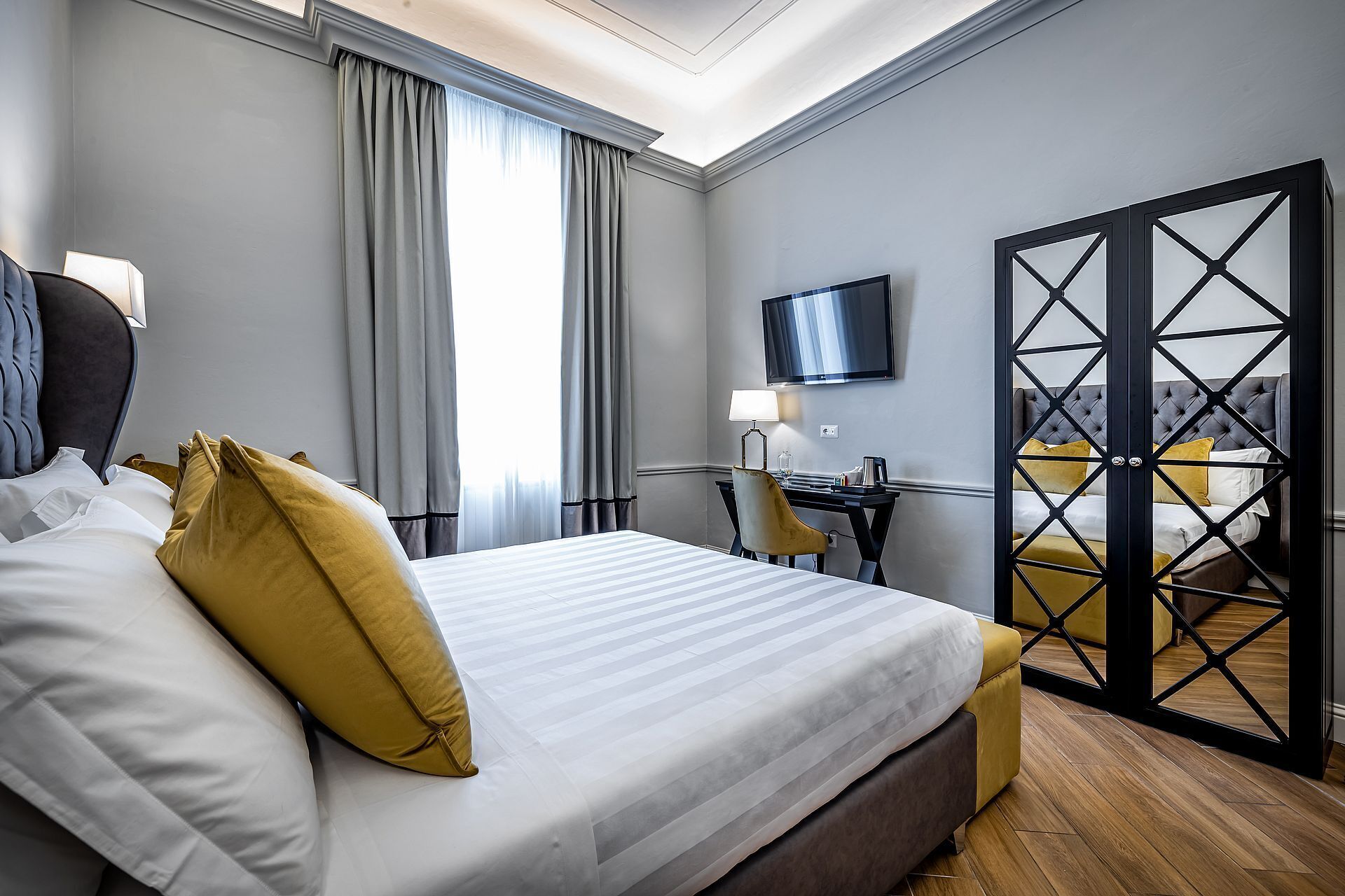 Ein Hotelzimmer mit Bett, Schreibtisch, Stuhl, Fernseher und einer Schiebetür.