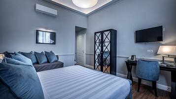 A hotel room with a bed, a desk, a chair, a TV, and a wardrobe.