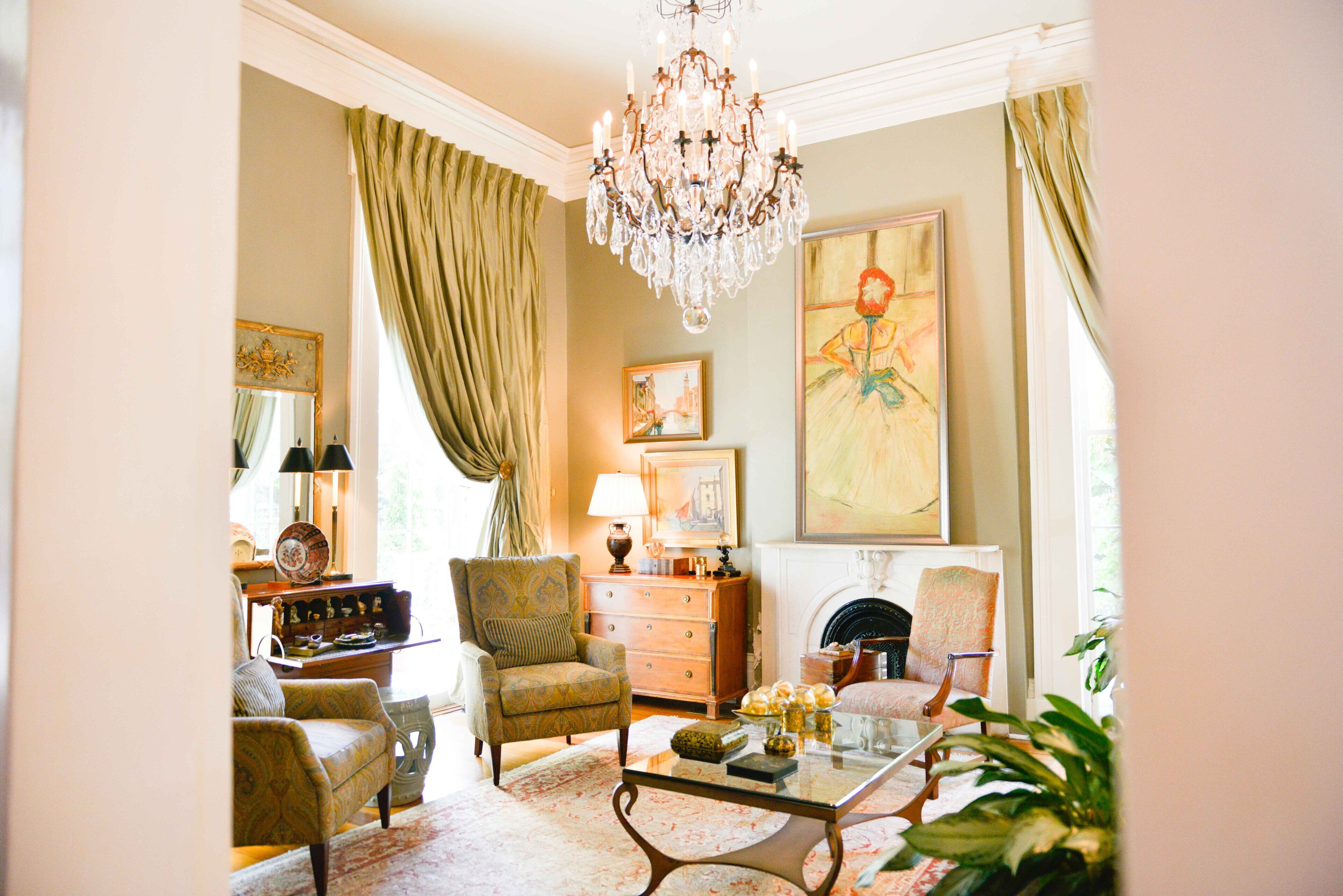 A traditional living room with a chandelier, a fireplace, and classic furniture.