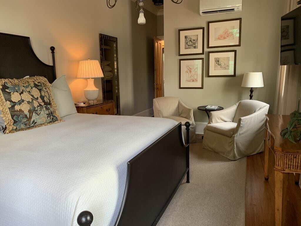 Una habitación de hotel con una cama grande, dos sillas, una mesita y decoración en la pared.