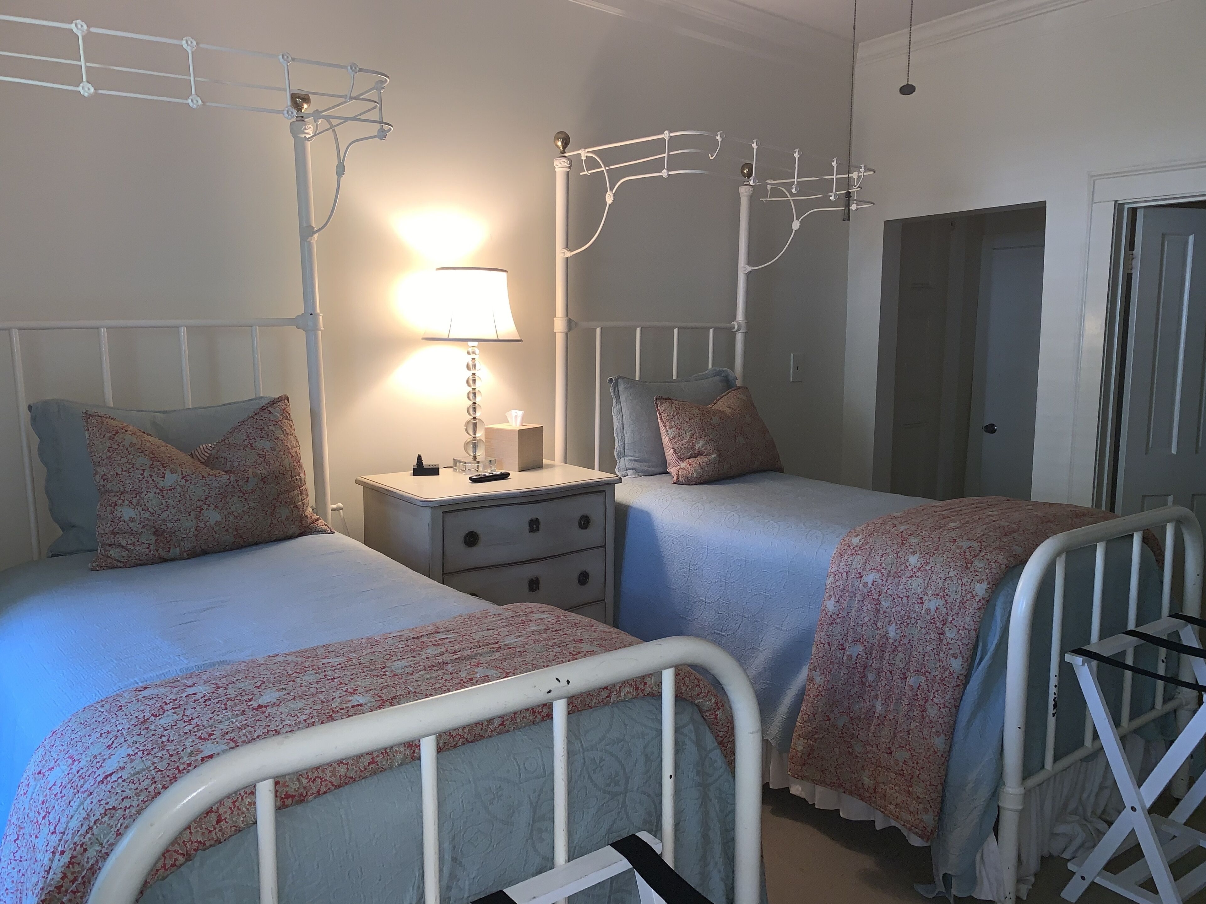 A bedroom with two beds, a bedside table with a lamp, and a wardrobe.