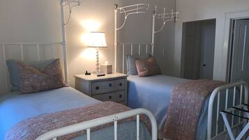 A bedroom with two beds, a bedside table with a lamp, and a wardrobe.
