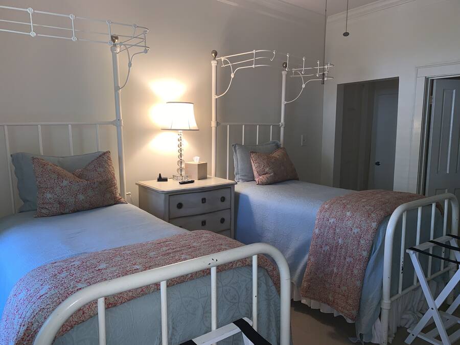 A bedroom with two beds, a bedside table with a lamp, and a wardrobe.