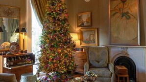 A cozy living room with a tall, decorated Christmas tree, a chandelier, and a fireplace. - Terrell House Bed & Breakfast (New Orleans)