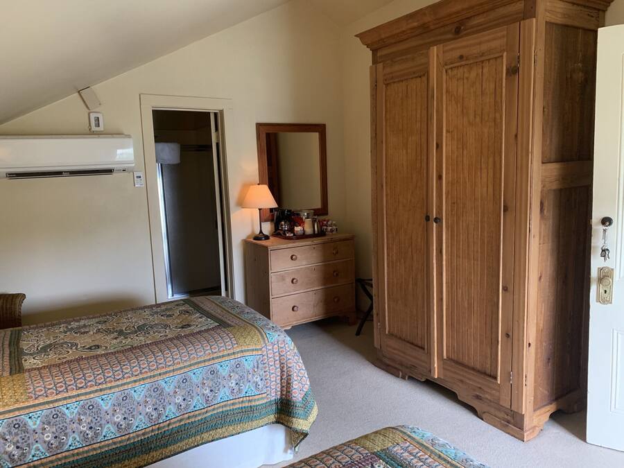 Ein Schlafzimmer mit Bett, Kommode, Kleiderschrank und Deckenventilator.
