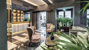 A modern lobby with a reception desk, seating area, and large windows. - Hotel Zara (Rome)