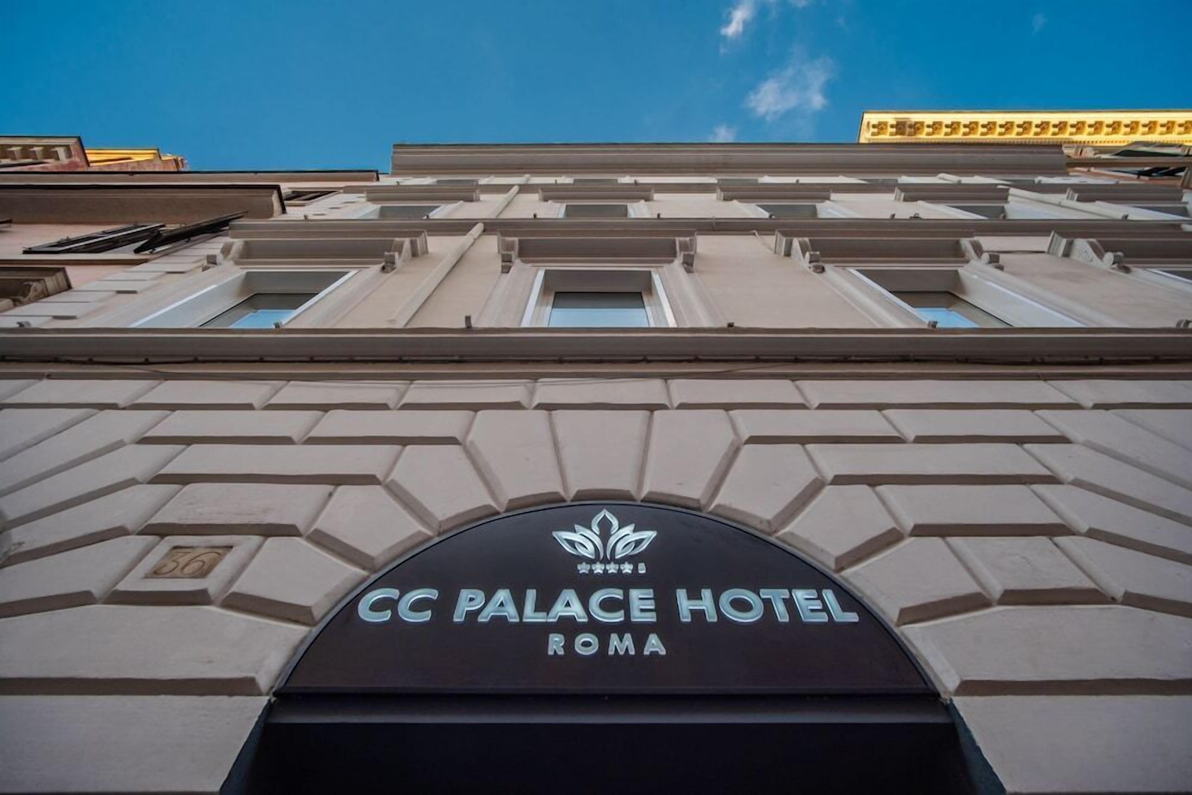 The exterior of the CC Palace Hotel in Roma with a prominent entrance and a clear sky in the background.