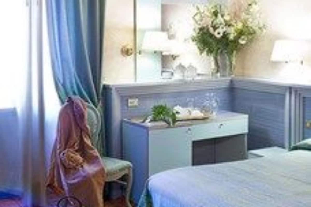 A hotel room with a bed, a vanity with a mirror, a dresser, and a chair.