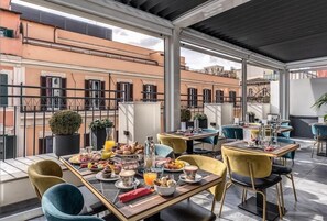 A rooftop dining area with tables set for breakfast, outdoor seating, and a view of the cityscape. - Hotel Zara (Rome)
