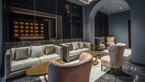 A modern lounge area with sofas and armchairs, a marble floor, and a wall with a built-in bookshelf. - Hotel Zara (Rome)