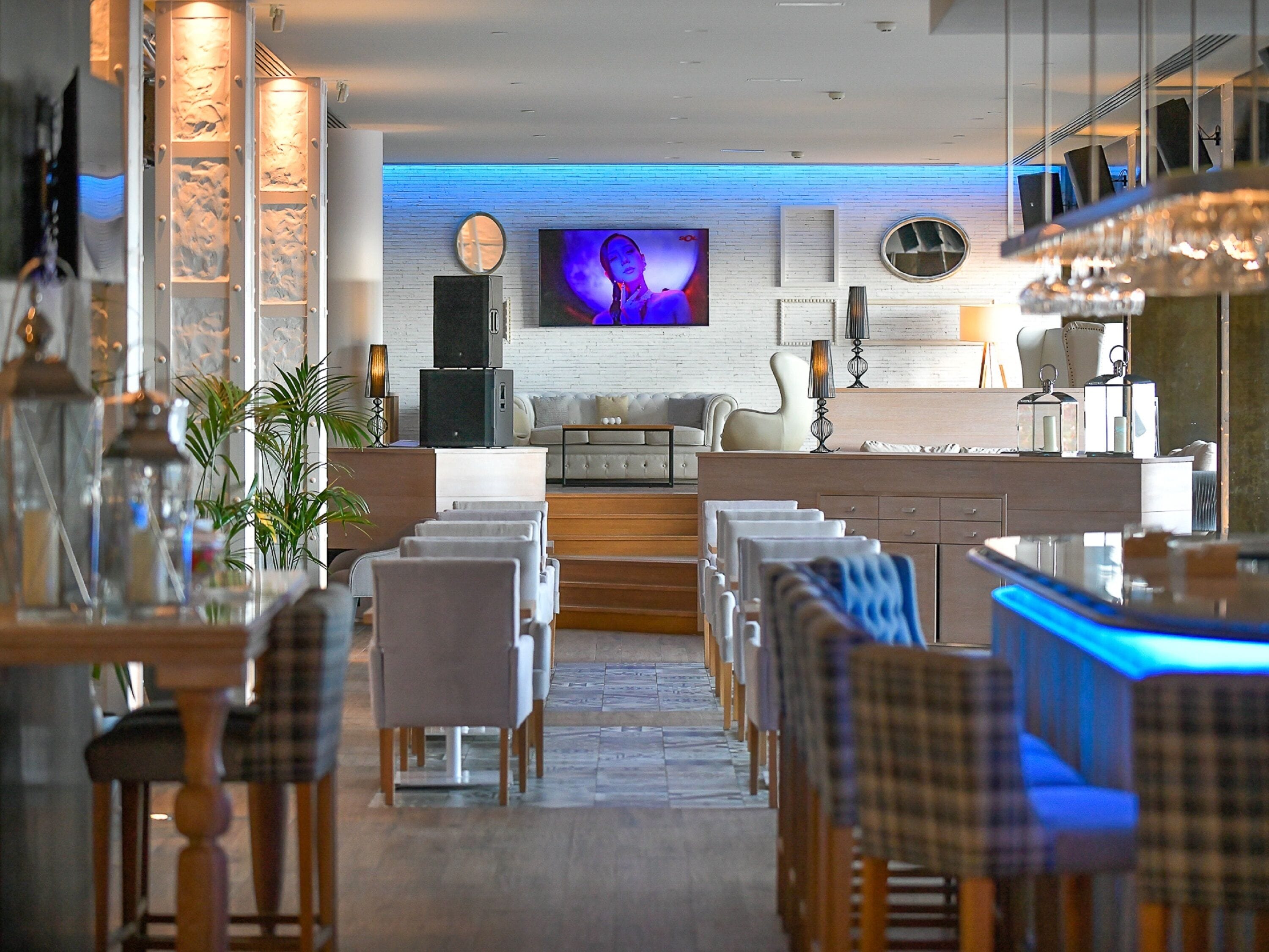 Un espace de restauration moderne avec une longue table, des chaises et un bar éclairé de lumière bleue.