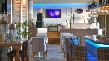 Un espace de restauration moderne avec une longue table, des chaises et un bar éclairé de lumière bleue.