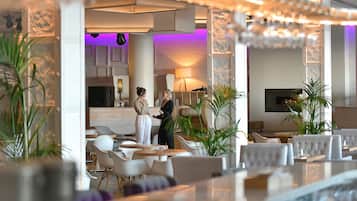 En modern hotellobby med en receptionsdisk, en sittgrupp och en bar.