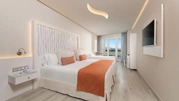 A modern hotel room with a large bed, bedside tables, a flat-screen TV, and a view of the city.