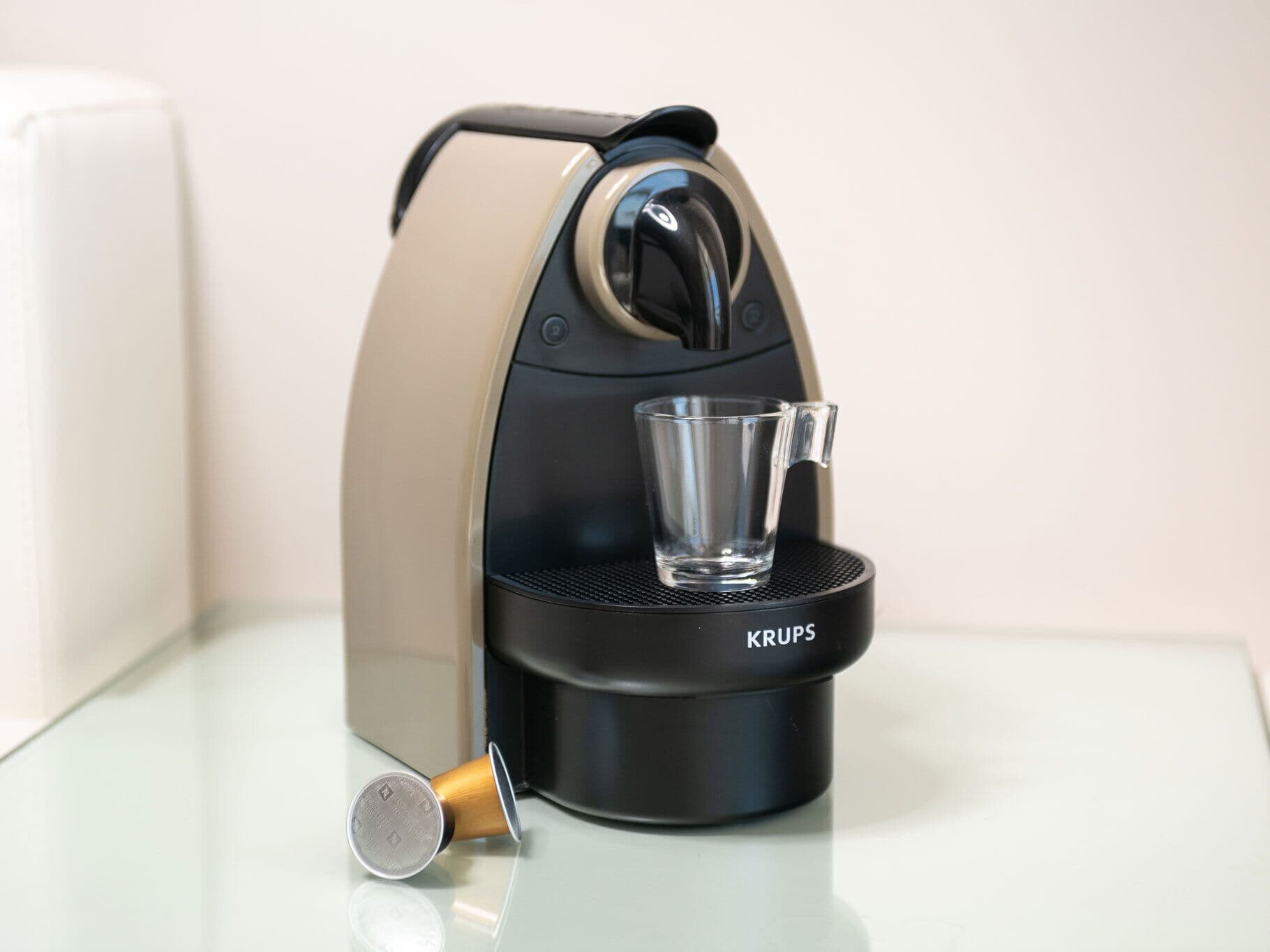 A KRUPS coffee machine with a glass cup on its drip tray.