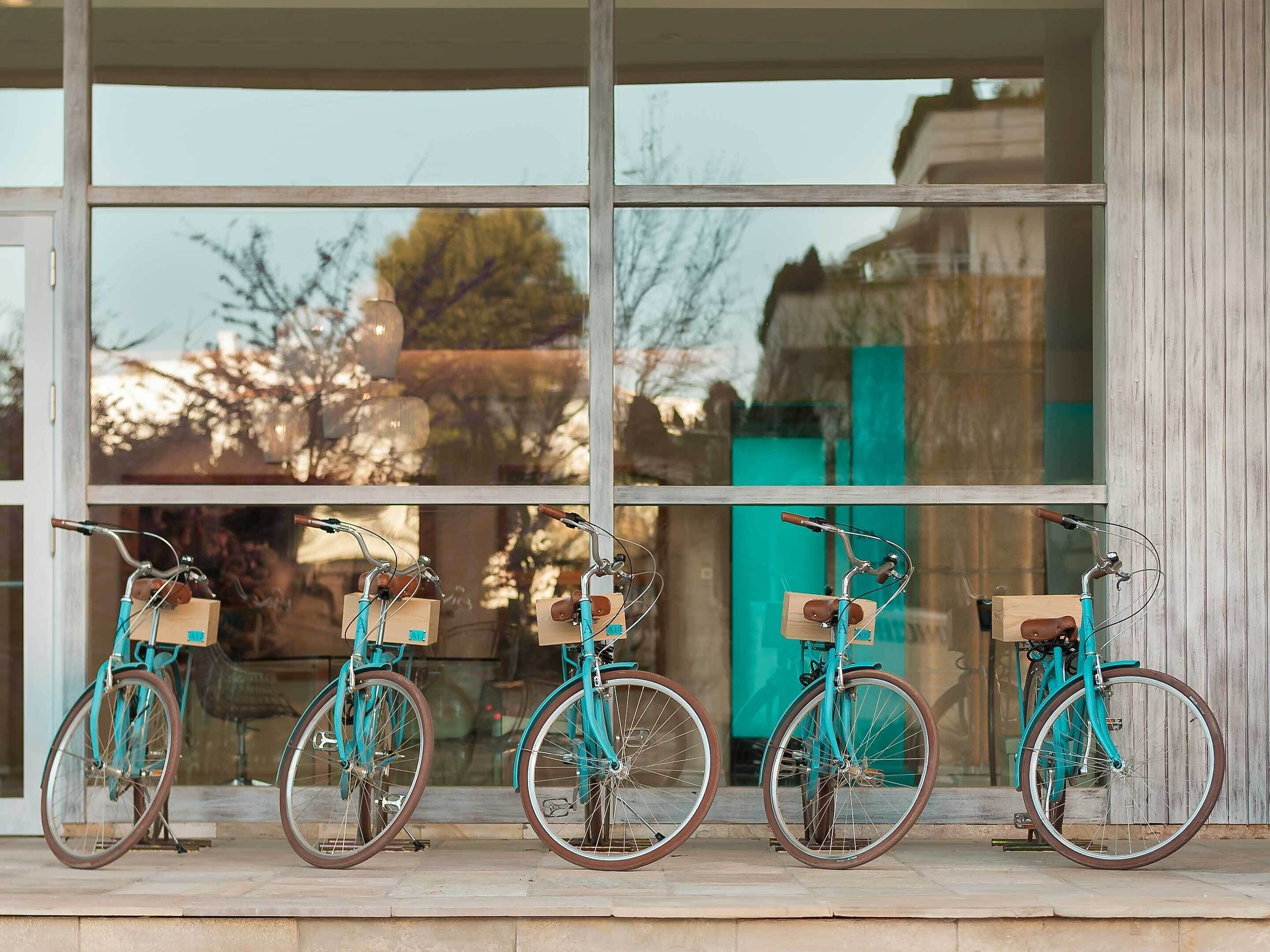 Four bicycles parked in front of a building with large windows.