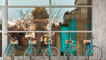 Four bicycles parked in front of a building with large windows.