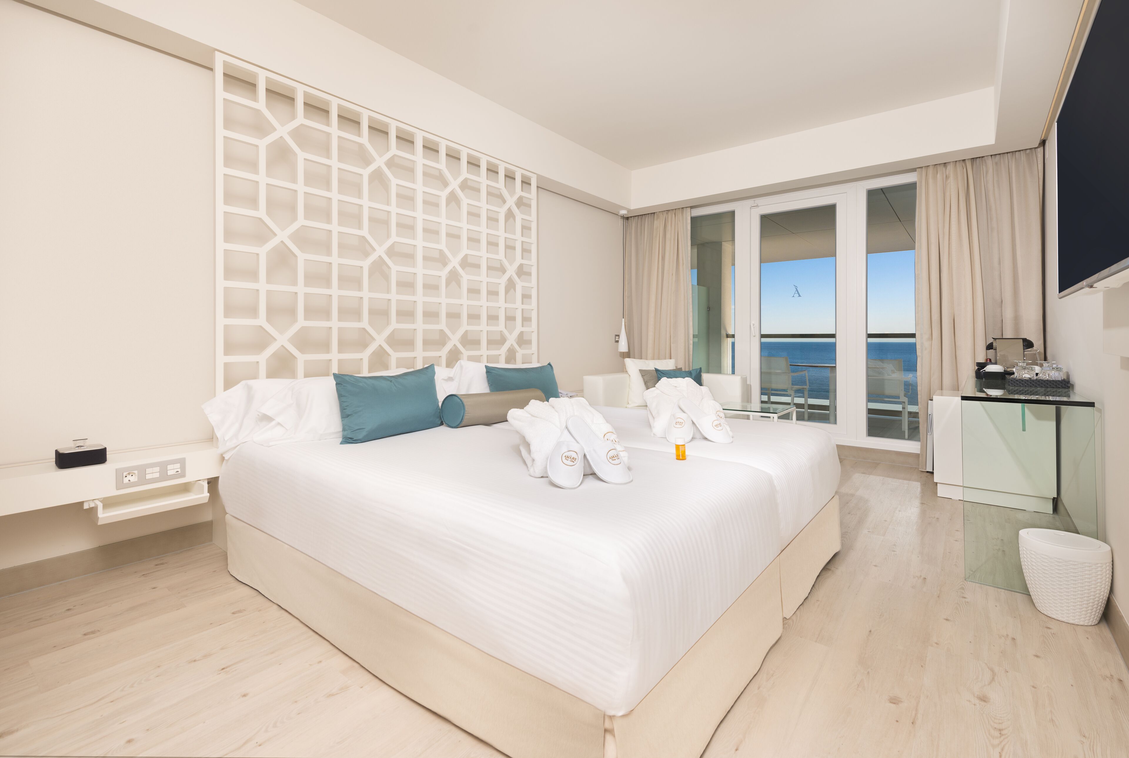 Ein modernes Hotelzimmer mit einem großen Bett, einem Glastisch und Meerblick.