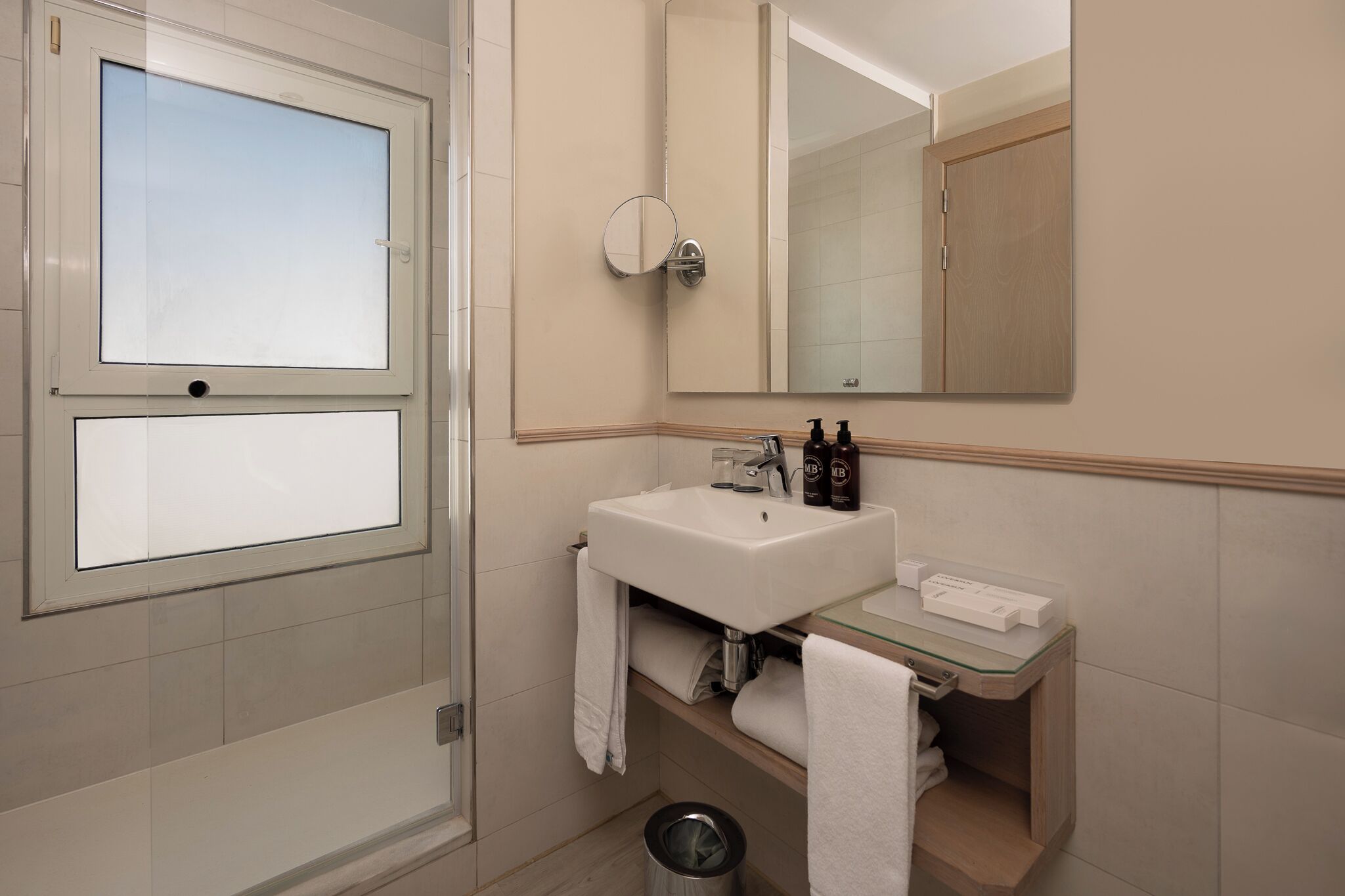 A bathroom with a window, a sink, a mirror, and a towel rack.