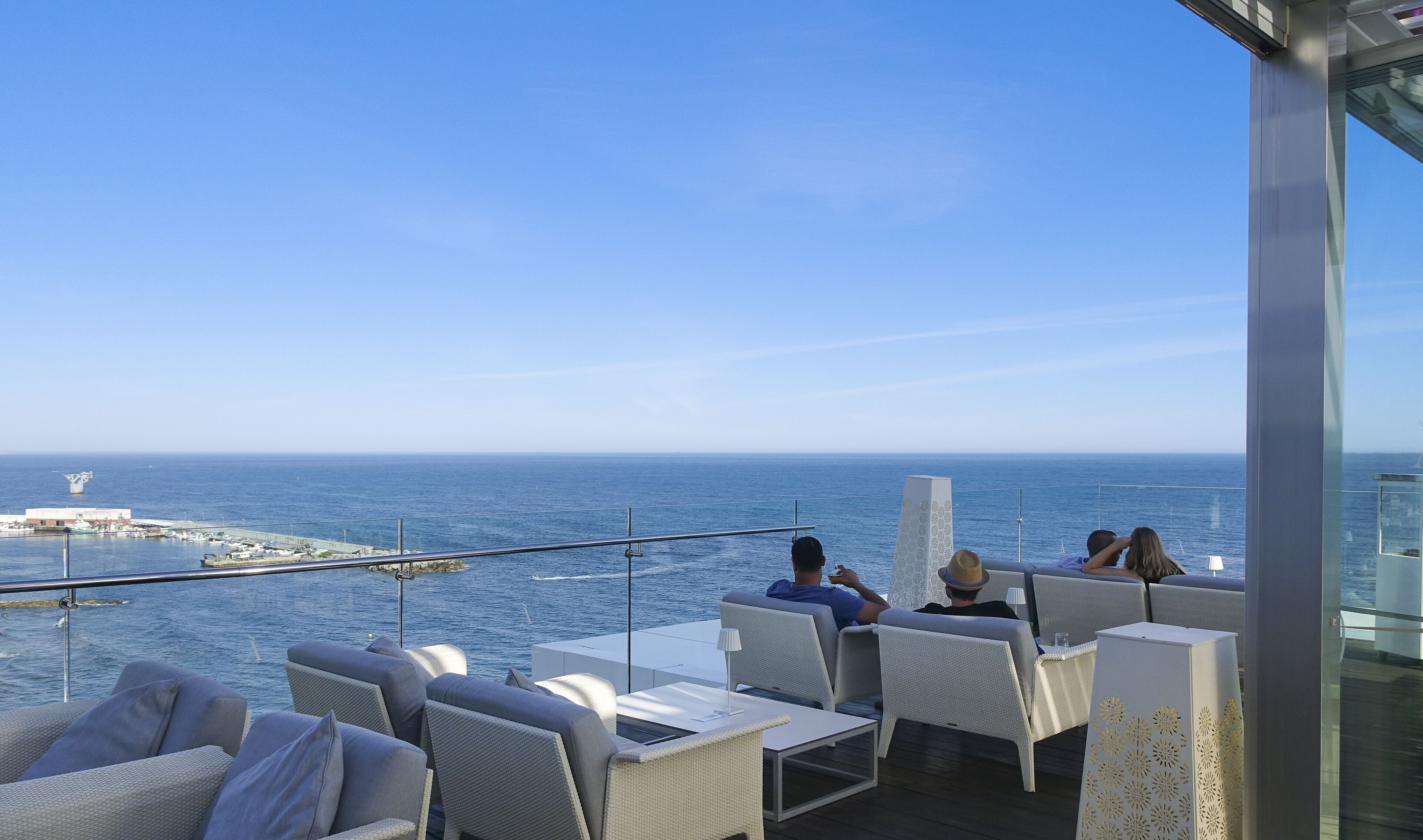 A balcony with outdoor seating overlooking the sea.