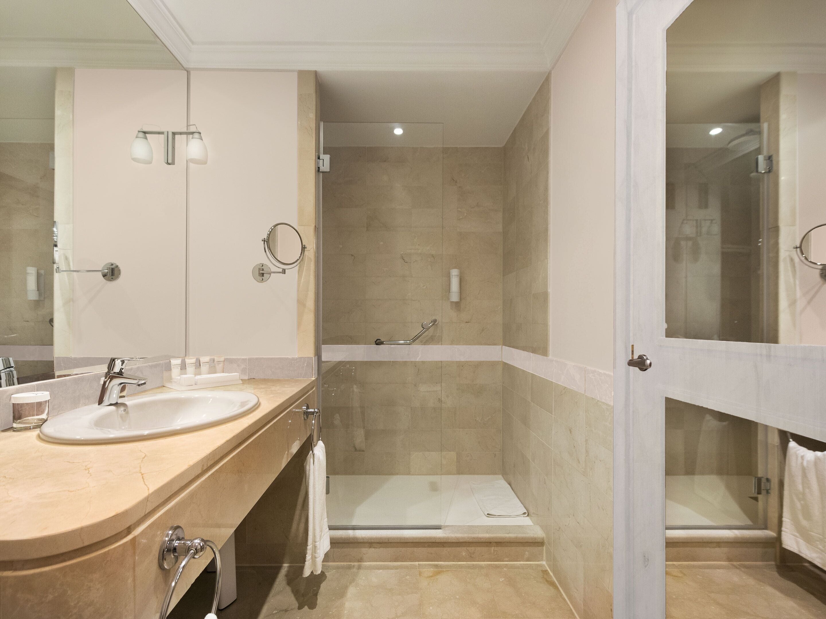 Ein modernes Badezimmer mit einem Doppelwaschbecken, einer Duschkabine aus Glas und einer begehbaren Dusche.