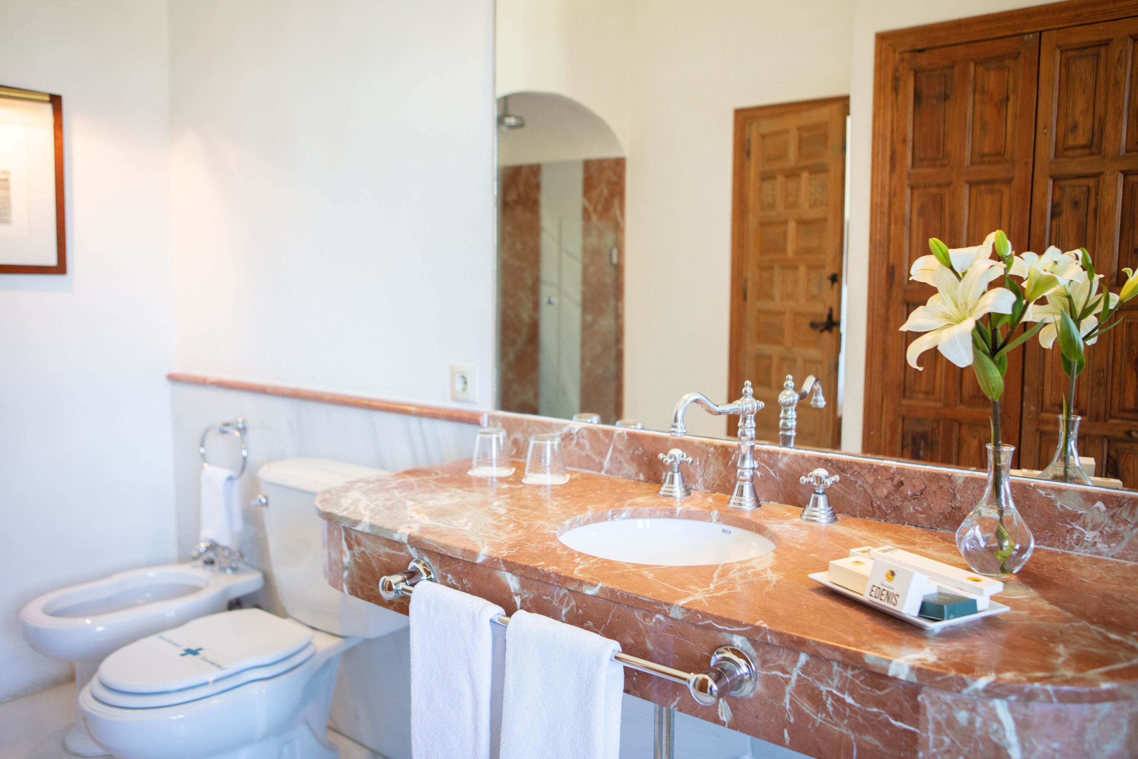 A bathroom with a marble sink, a toilet, and a mirror.