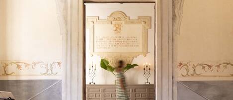 A marble staircase leading to a door with a plaque, a potted plant, and a candle holder.