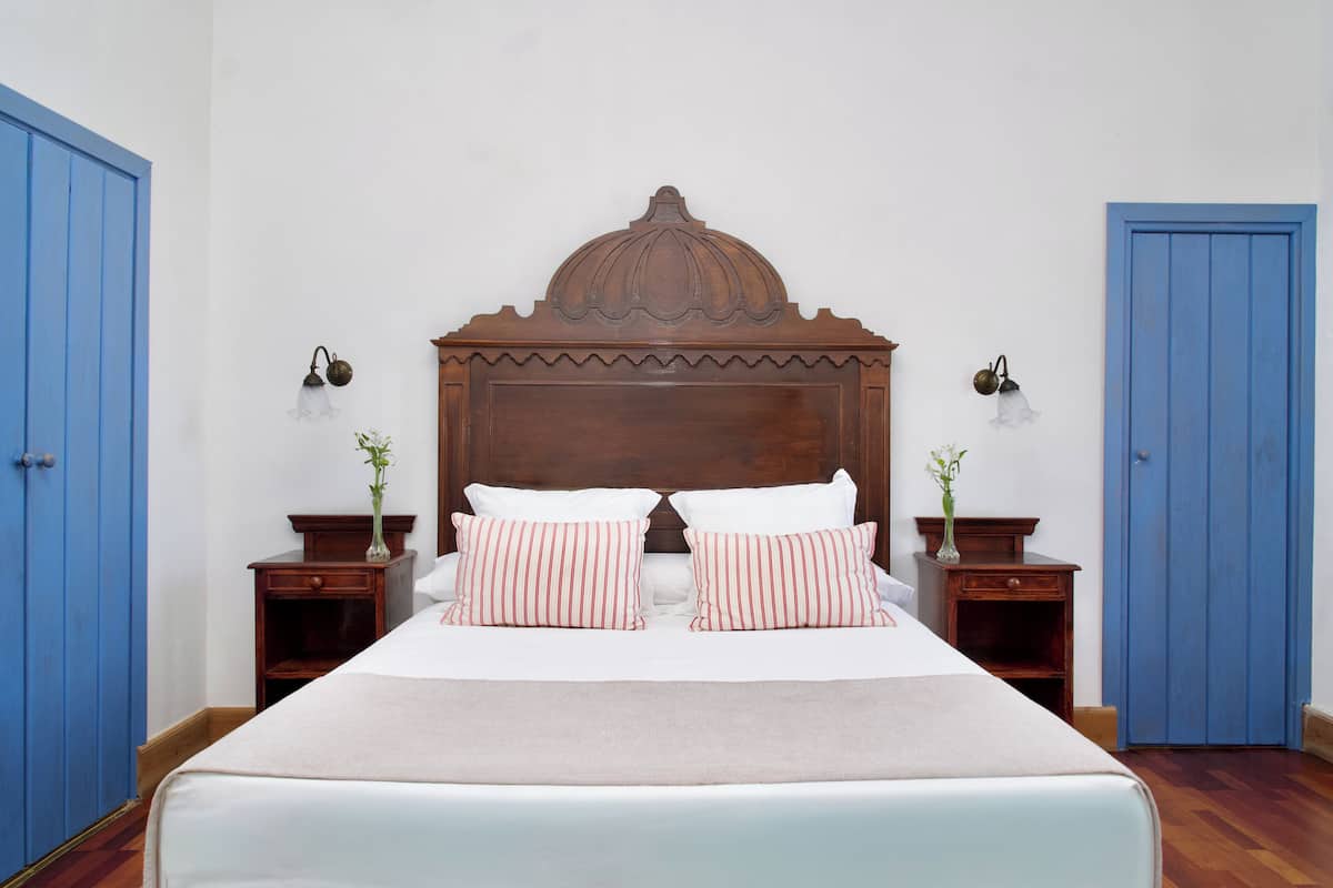 Un dormitorio con una cama grande, dos mesitas de noche y un cabecero de madera.
