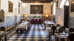 Un comedor con suelo a cuadros, vigas de madera y mesas dispuestas para comer.