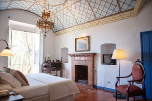 Relax in this serene retreat with a large bed, fireplace, and stunning view of palm trees.