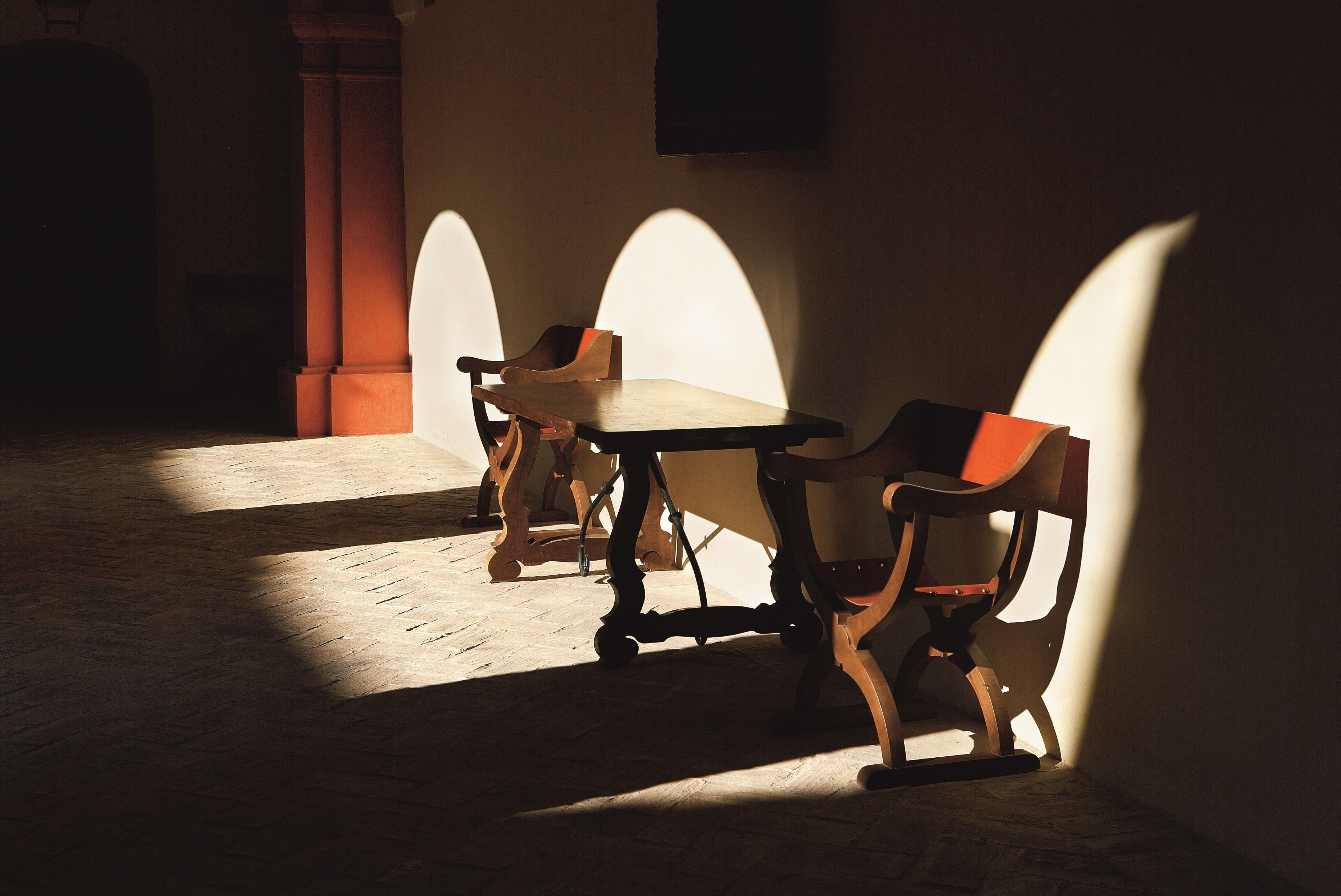 Een kamer met een tafel, stoelen, een open haard en een kolom.