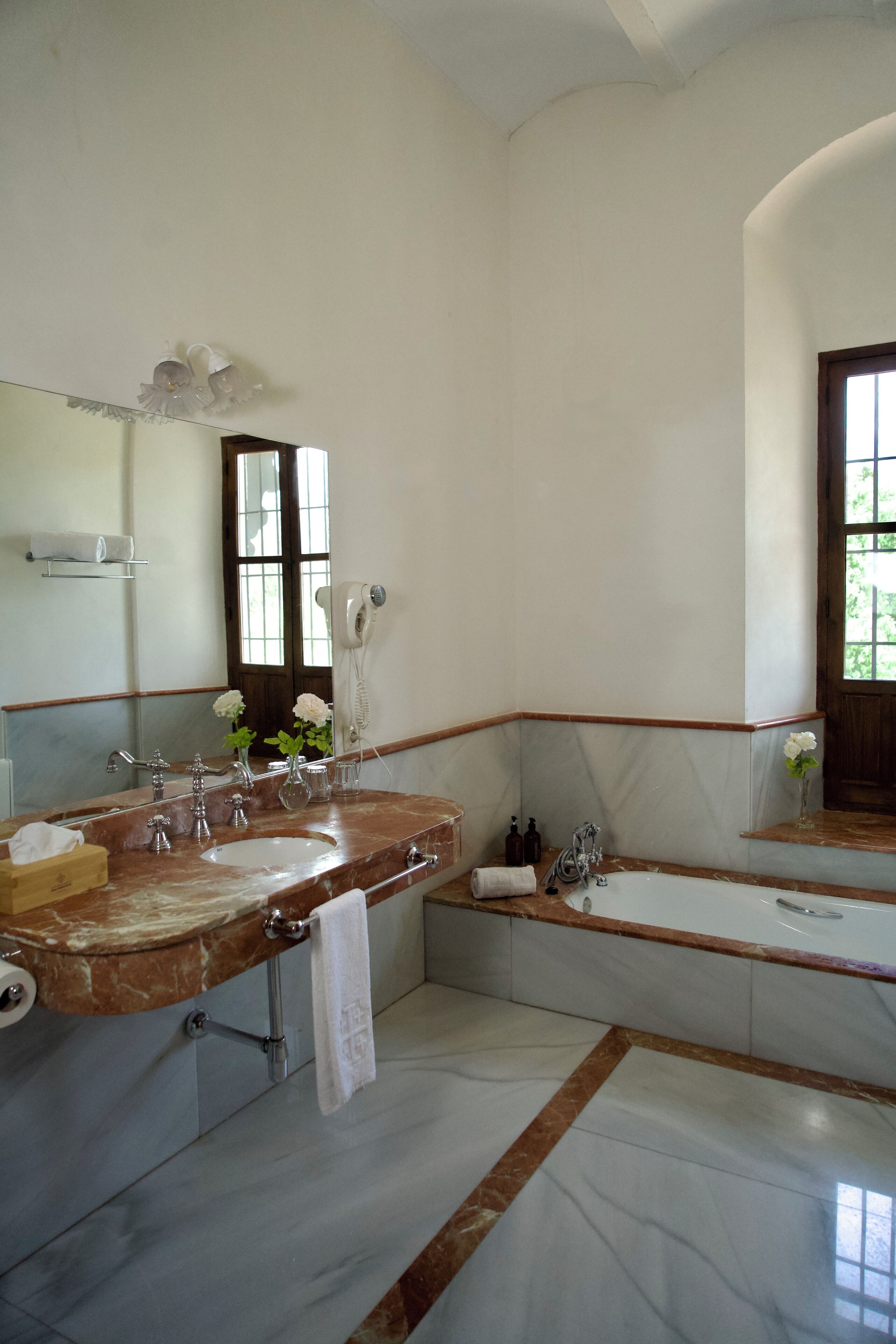 Une salle de bain avec un meuble-lavabo en marbre, une baignoire et un grand miroir.