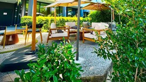 Un área de estar al aire libre con mobiliario de madera y una gran sombrilla.