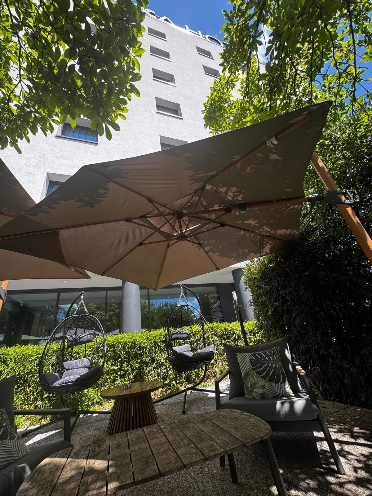 An outdoor seating area with a hanging chair, a round table, and a large umbrella.