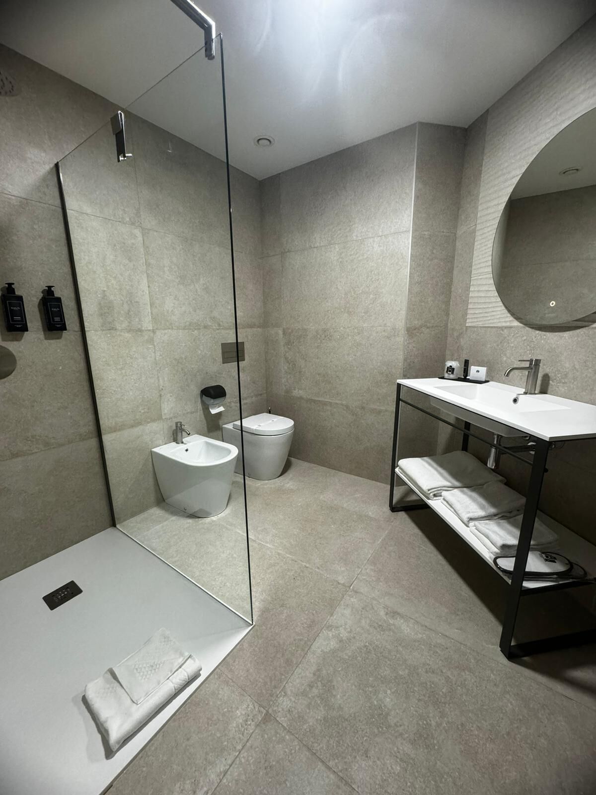 A modern bathroom with a glass shower enclosure, a white sink, and a toilet.