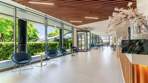 Un interior moderno con paredes de vidrio, listones de techo de madera y zonas de estar.