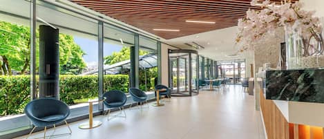 A modern interior with glass walls, wooden ceiling slats, and seating areas.