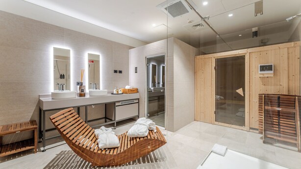 Un baño moderno con un banco de madera, un espejo grande y una cabina de ducha de vidrio.
