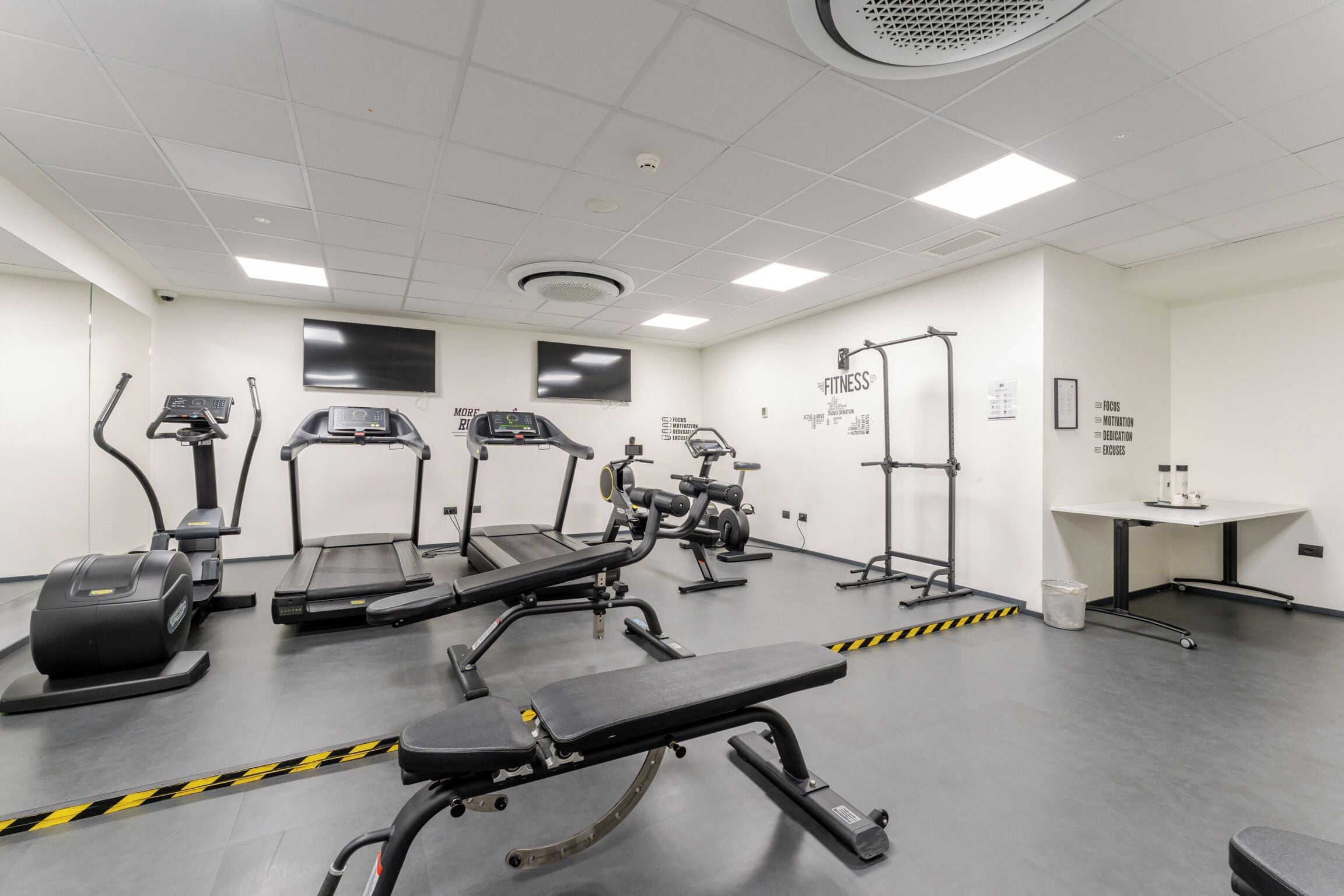 A gym with treadmills, elliptical machines, and weight benches.