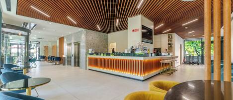 A modern hotel lobby with a reception desk, seating areas, and a wooden ceiling design.