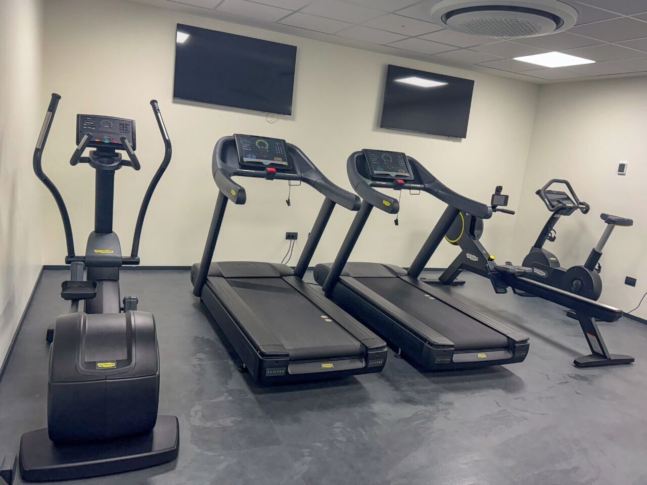 A gym with treadmills, an elliptical, and a stationary bike.