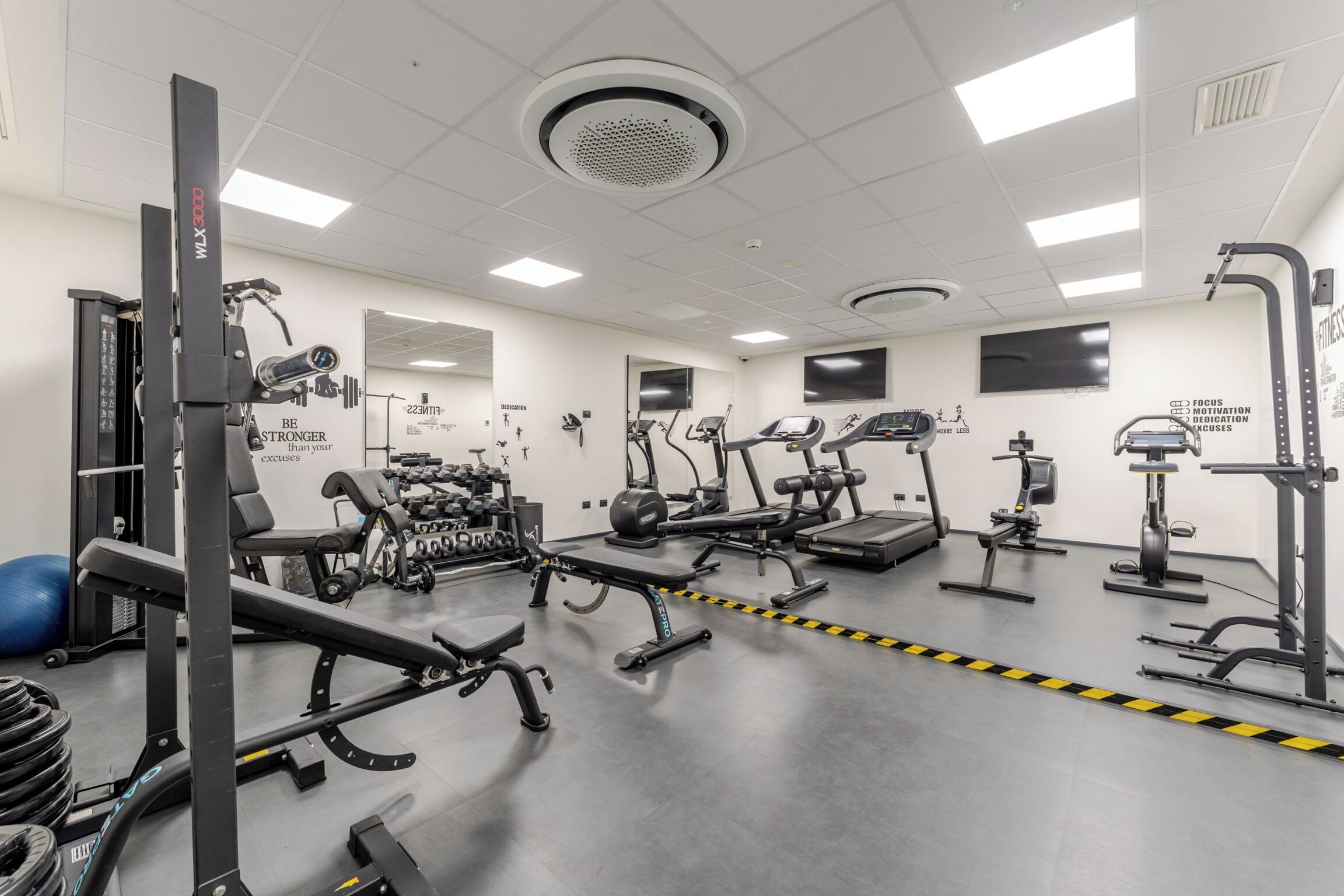 A gym with various exercise equipment, mirrors, and motivational posters.