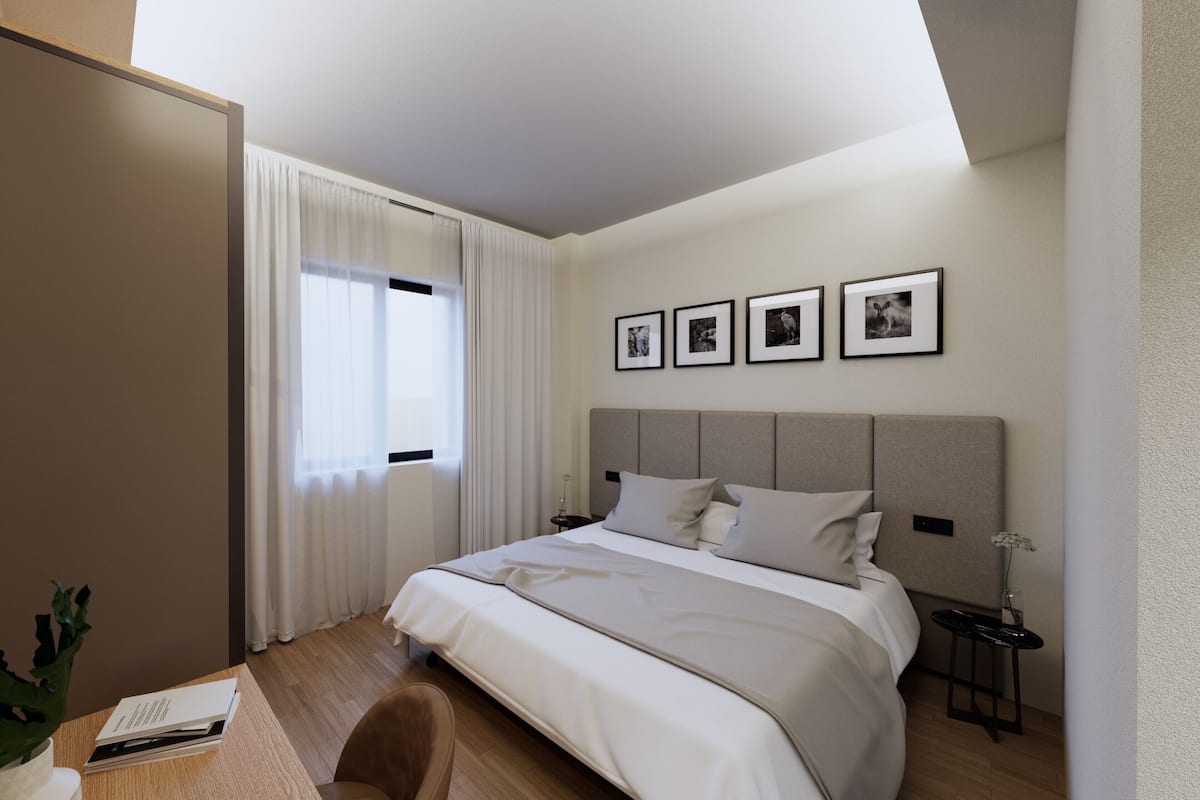 A hotel room with a bed, a desk, a chair, a nightstand, a plant, and a window with curtains.