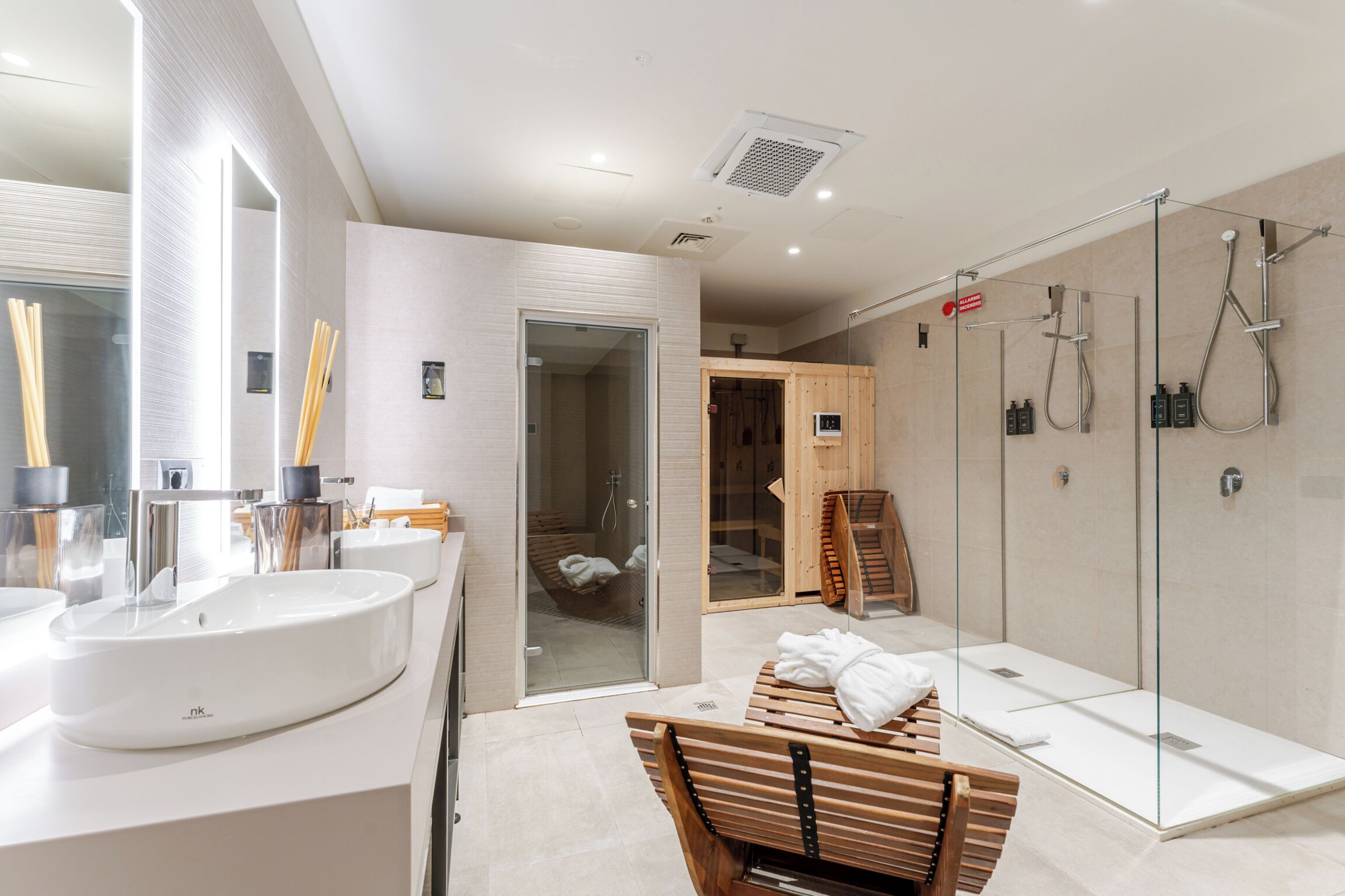 A modern bathroom with a large sink, glass shower enclosure, and a wooden bench.
