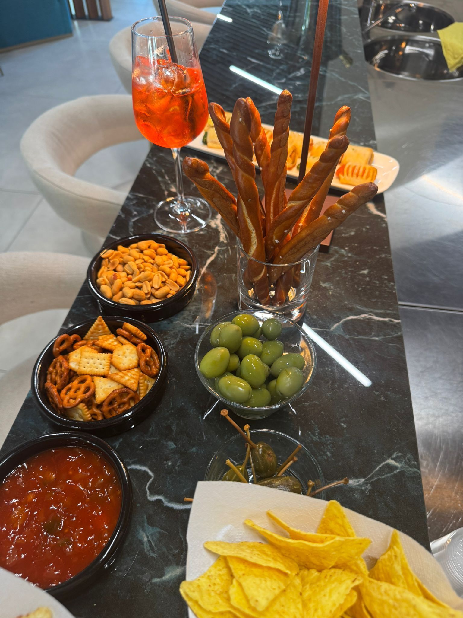 A buffet table with various snacks, including pretzels, olives, and chips.