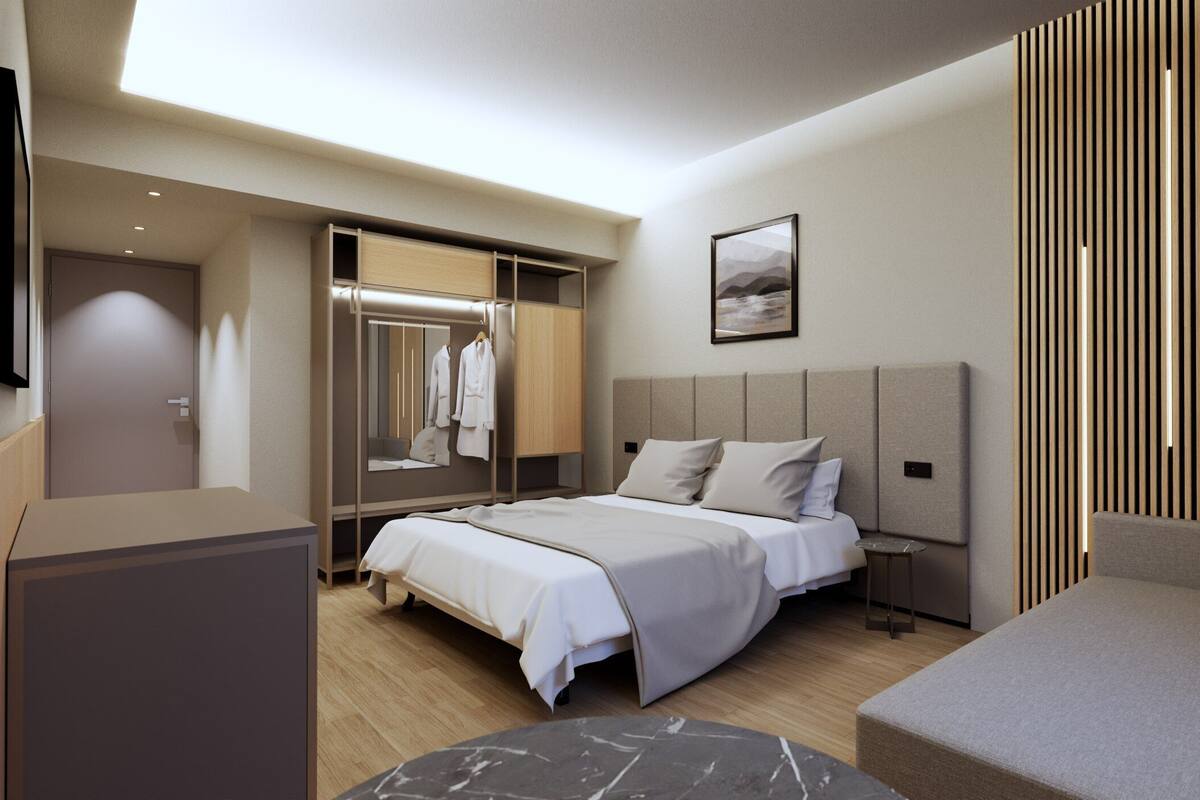 A modern hotel room with a bed, bedside table, and a seating area.
